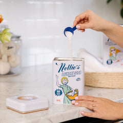 Image of someone pouring a small scoop-worth of laundry soda into a tin of Nellie's Laundry Soda.